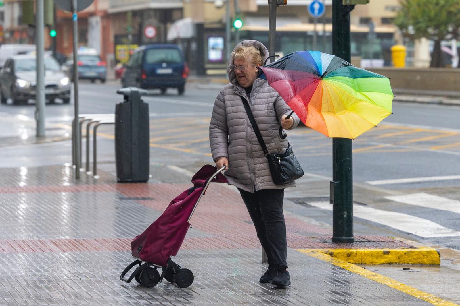Una mujer intenta protegerse de la lluvia pese al fuerte viento, en la Avenida principal de Cádiz este martes.