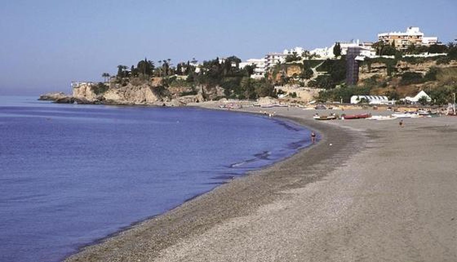 2. Burriana (Nerja)

Numerosas urbanizaciones de casitas con jardín, ubicadas sobre escarpadas rocas, rodean esta extensa playa que es, sin lugar a dudas, la más conocida y turística de la costa nerjeña. Cuenta, además, con el distintivo Q de calidad turística, marca que representa la calidad en el sector turístico español, así como la Bandera Azul de la Unión Europea. El acceso principal es a la salida de Nerja en dirección Almería en la N-340, y a la derecha, a la altura de la urbanización Verano Azul. La playa está totalmente equipada y suele ser frecuentada por familias. El entorno es diverso y desde sus 800 metros de longitud se divisan montañas y acantilados. Se puede practicar windsurf, vela y submarinismo y jugar al voley. 

Foto: Turismo Costa del Sol