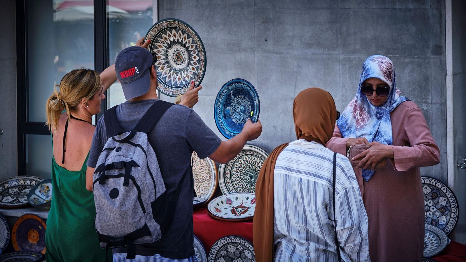 Unos jóvenes observan la calidad de la cerámica que vende Abdelati Kourtam.