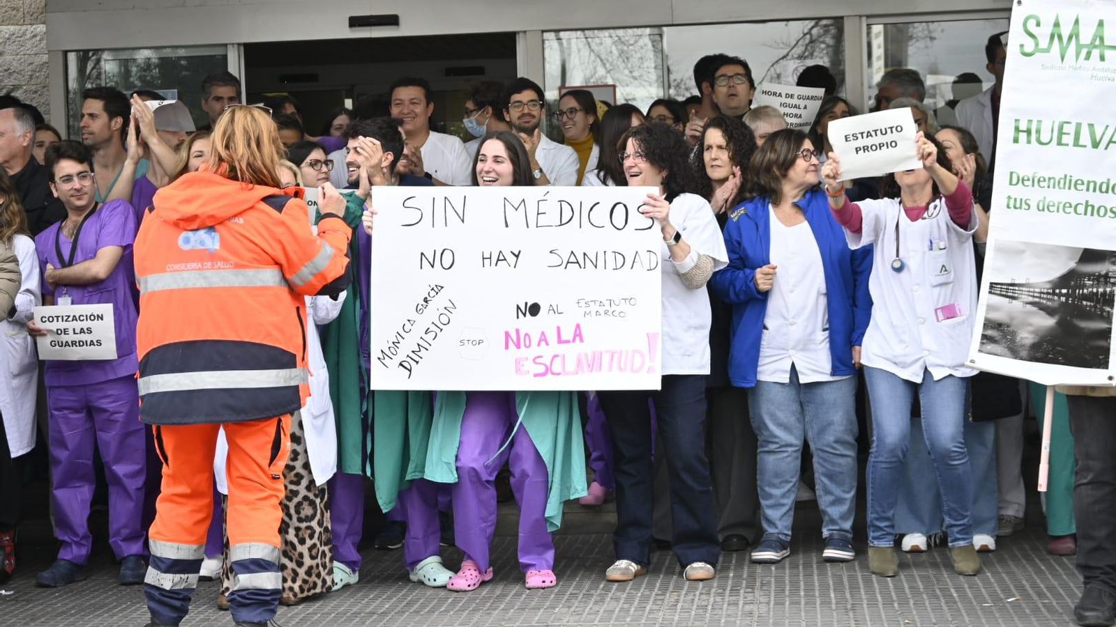 Personas sujetando pancartas reivindicativas frente al Hospital Juan Ramón Jiménez este lunes.