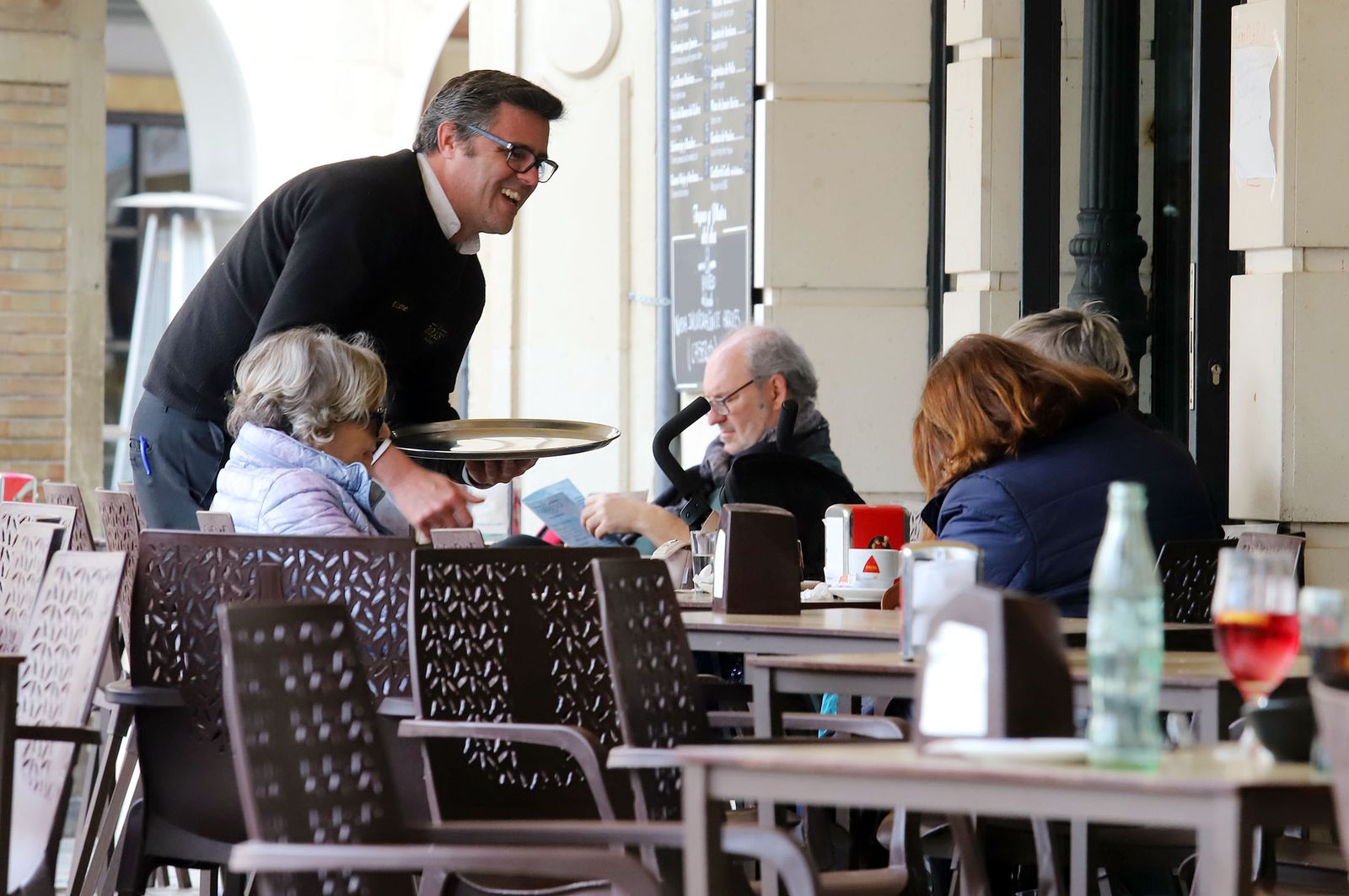 Un camarero atiende a unos clientes.