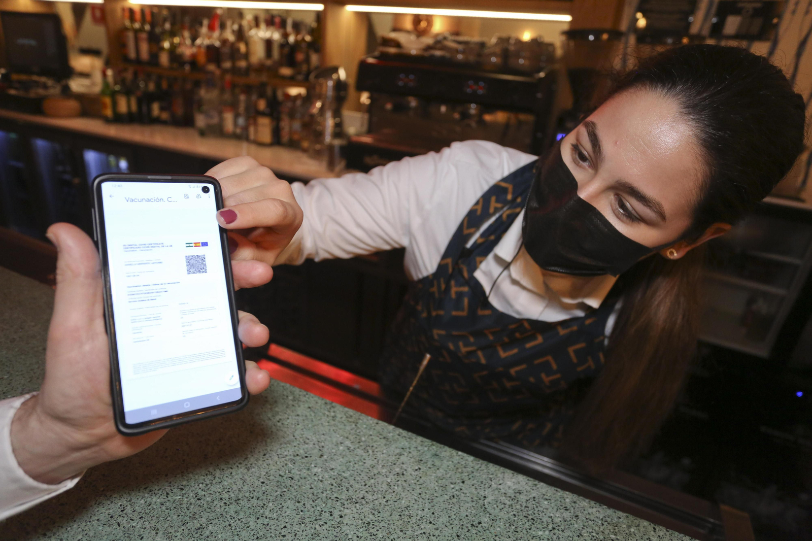 Hostelera revisa a un cliente el certificado Covid.