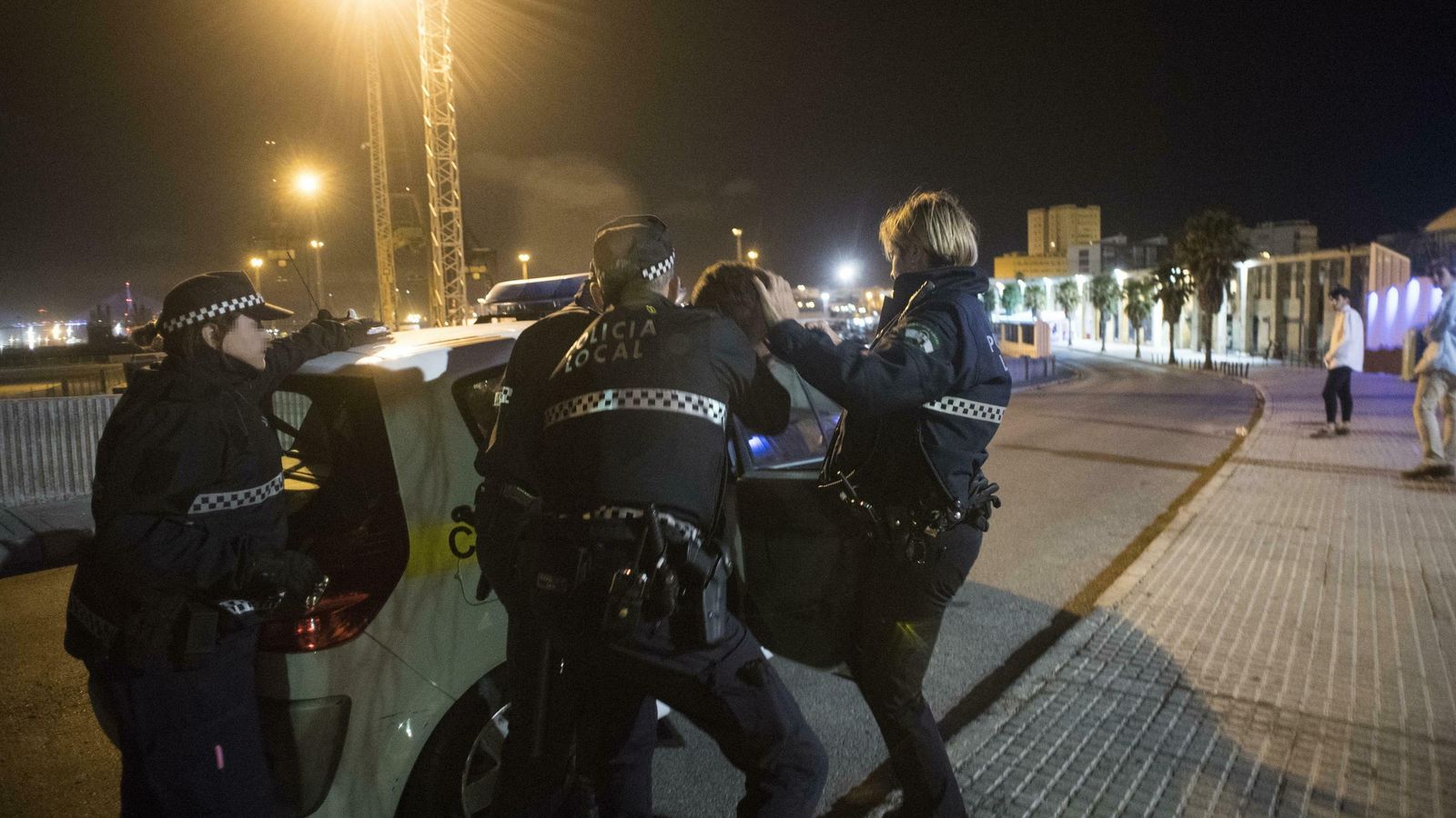 Varios agentes introducen a un detenido en un vehículo policial.