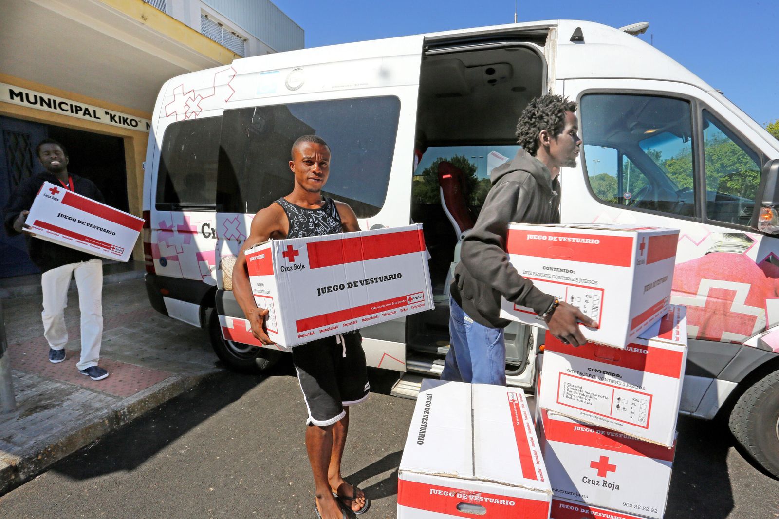 Migrantes colaborando con los voluntarios de Cruz Roja en el transporte de mercancías, el pasado viernes.