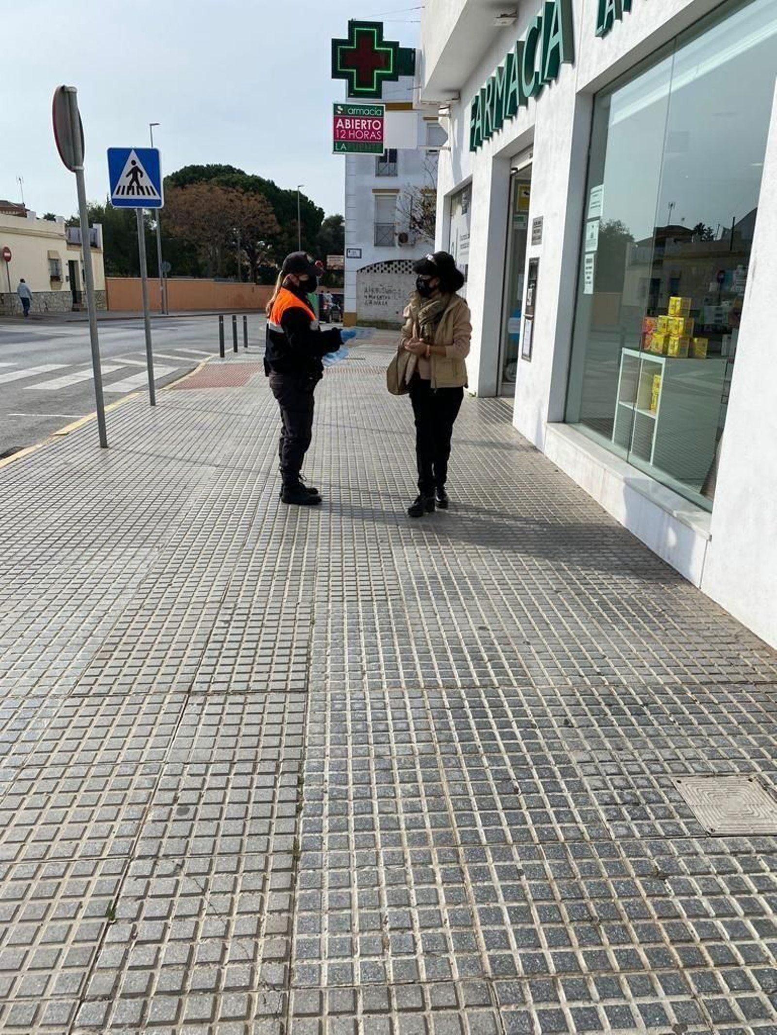 Una voluntaria de Protección Civil informa a una mujer sobre las medidas de seguridad.