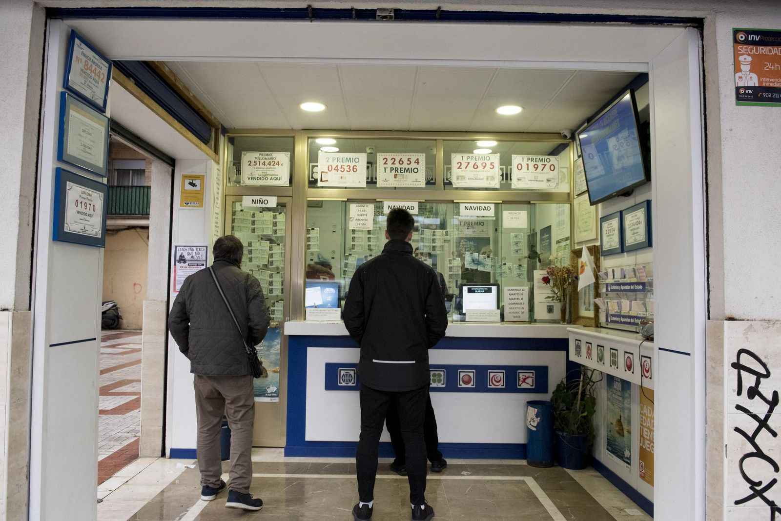 Varias personas aguardan en una administración de loterías.