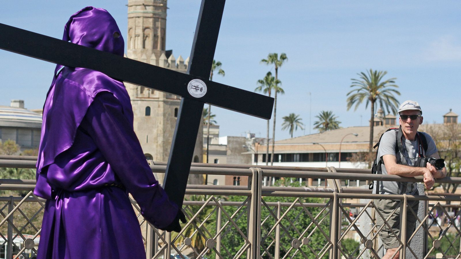 Un turista contempla el paso de un nazareno de Las Cigarreras.
