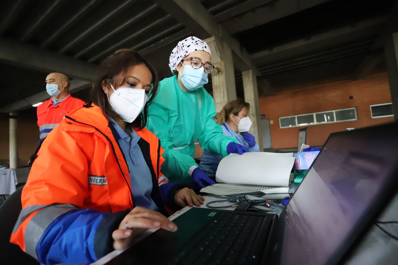 Maite, de pie, y sus compañeros revisan el listado de los convocados en el Autocovid del Nuevo Colombino.