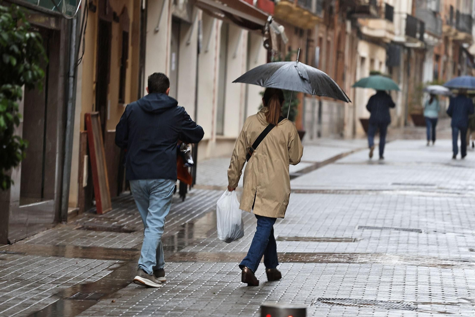 Varias personas por el centro de Huelva un día lluvioso.
