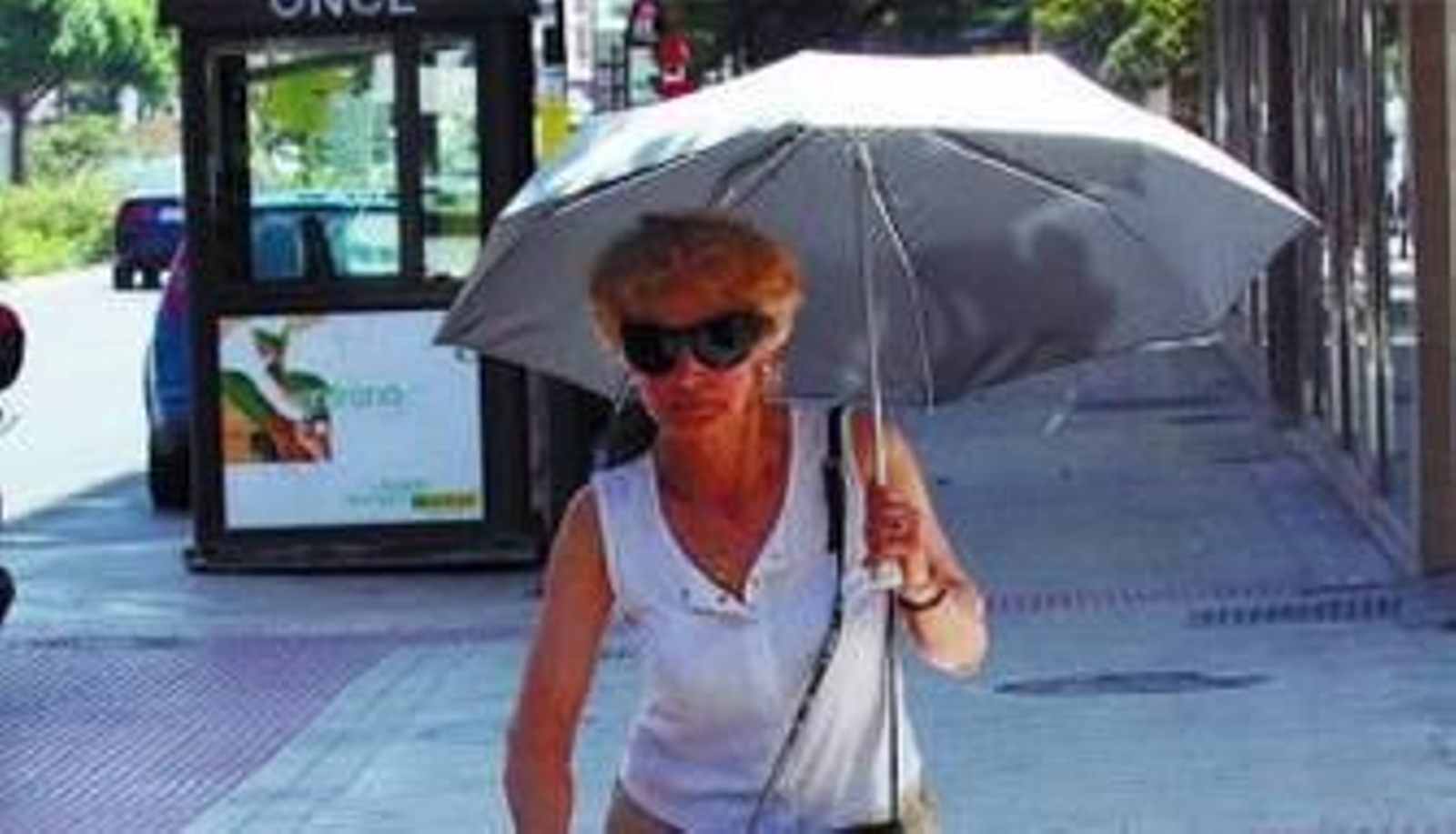 Una mujer se protege del sol con un paraguas.