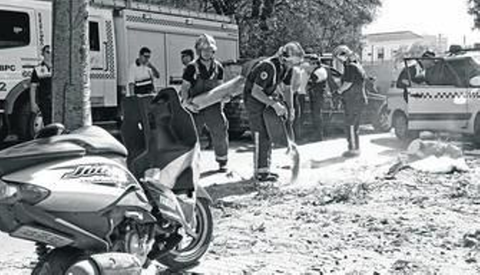 Los bomberos esparcen arena para tapar los restos del mortal accidente ocurrido ayer.