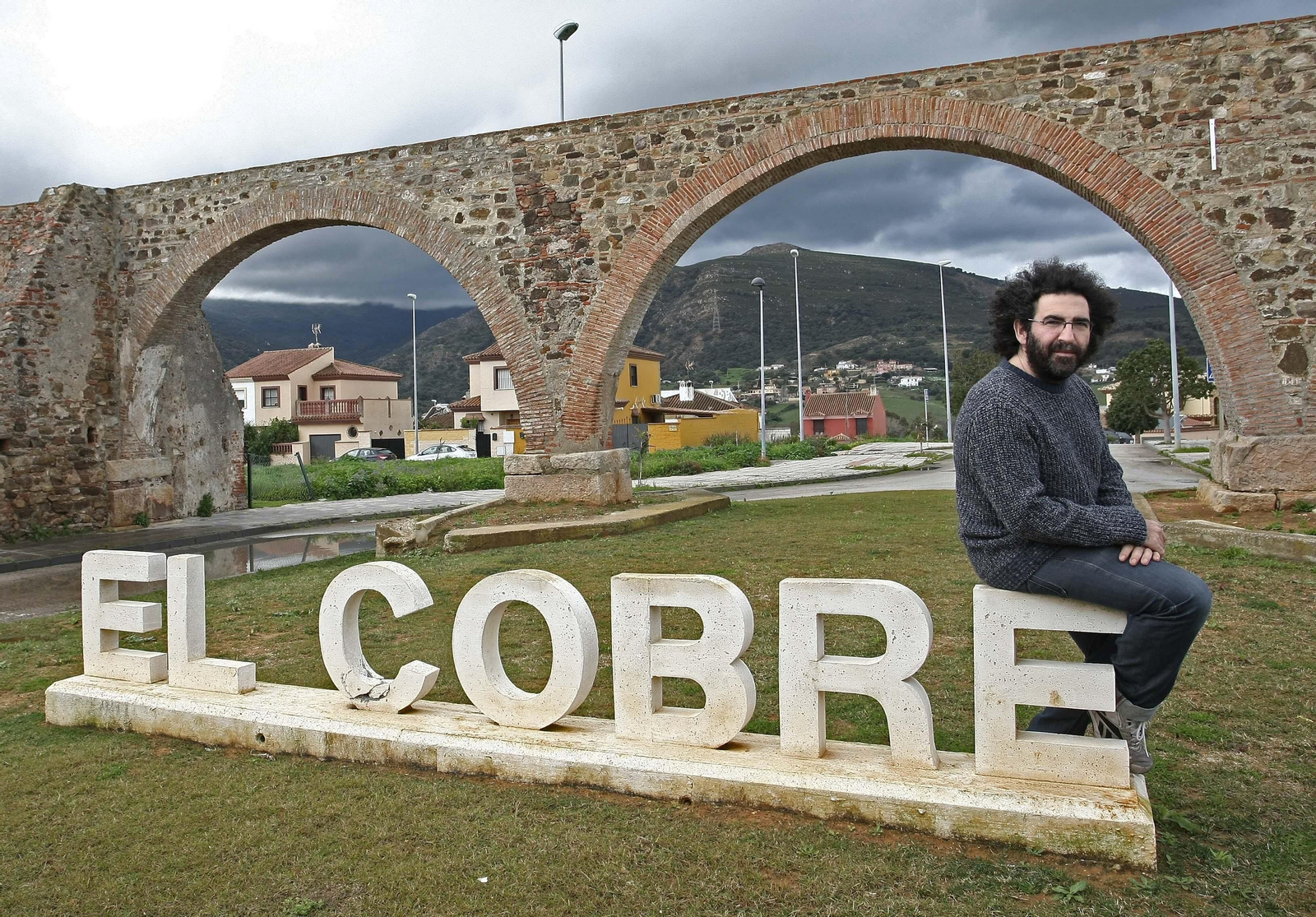 Antonio Romera, 'Chipi', sentado en las letras que anuncian El Cobre, su barriada, junto a los arcos.