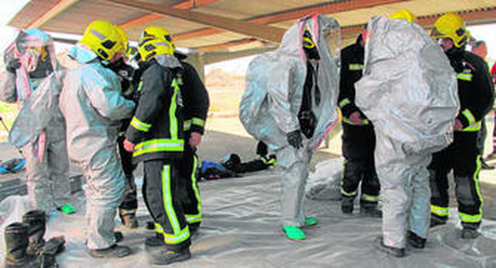 Los bomberos se enfundan los equipos de protección NBQ que en caso real deben utilizar.