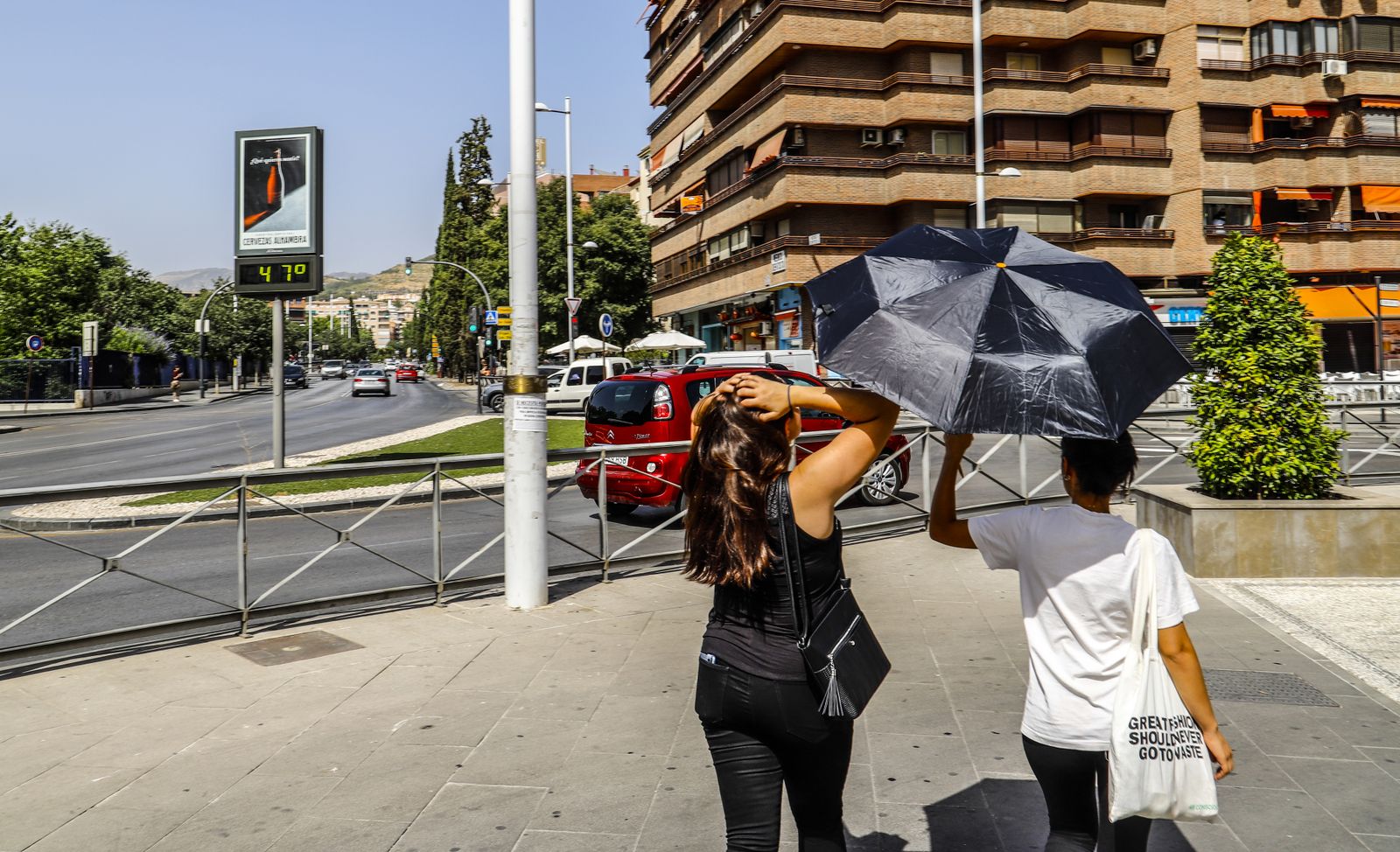 Dos viandantes portan un paragüas para aplacar el efecto del sol