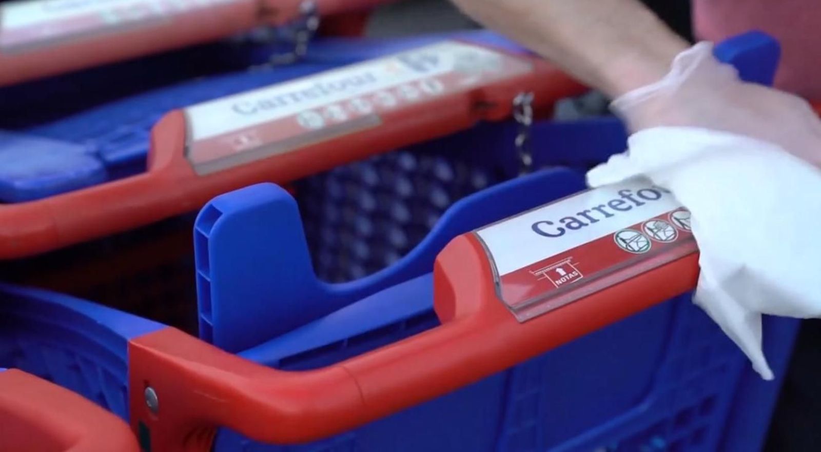 Un operario desinfecta un carro de Carrefour.