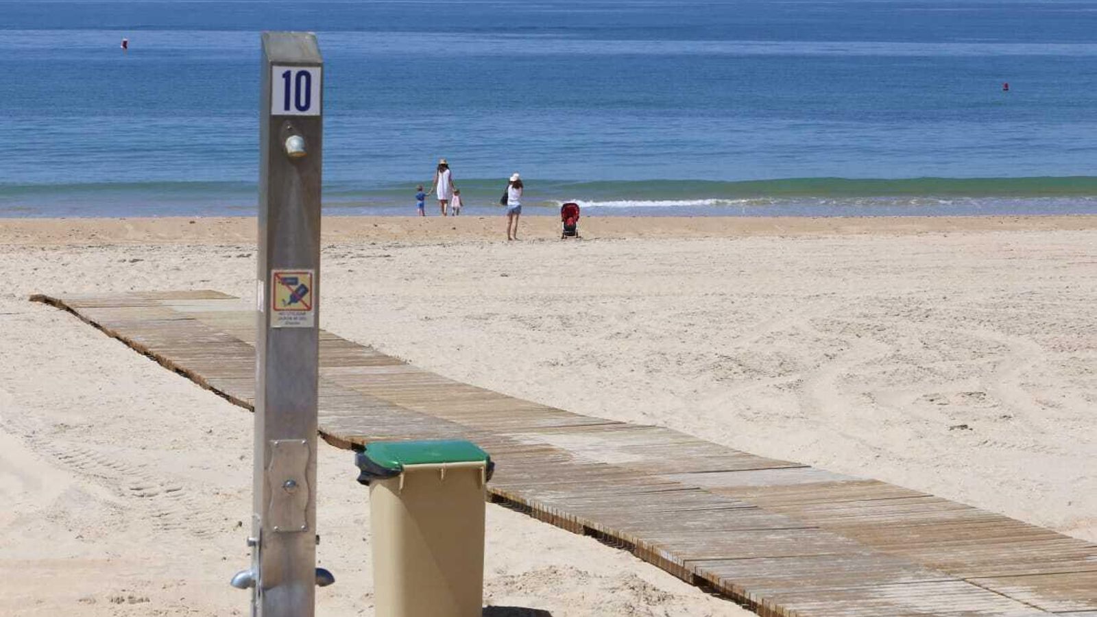 Vista de la playa de La Barrosa con algunas personas paseando por la orilla.