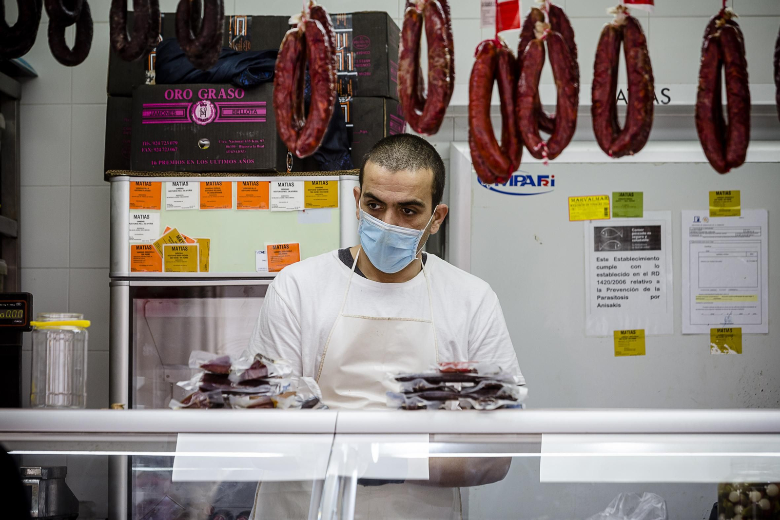 Un detallista del mercado central atiende con mascarilla a la clientela