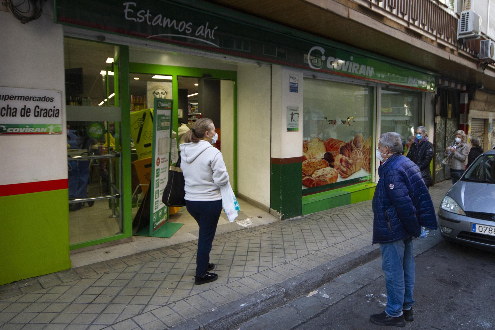 Clientes aguardan en la cola para entrar a comprar en el supermercado Covirán de Ancha de Gracia de Granada.