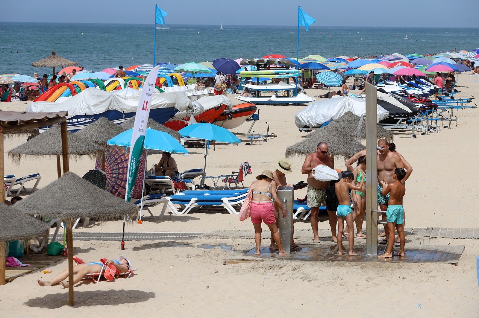 Una familia se refresca en las duchas de una playa onubense