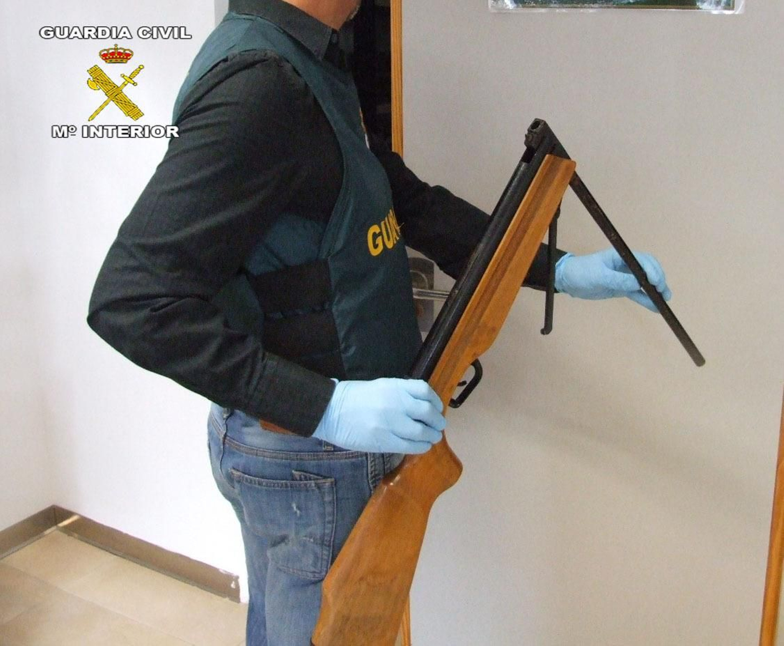 Un agente muestra el arma empleada en el crimen.