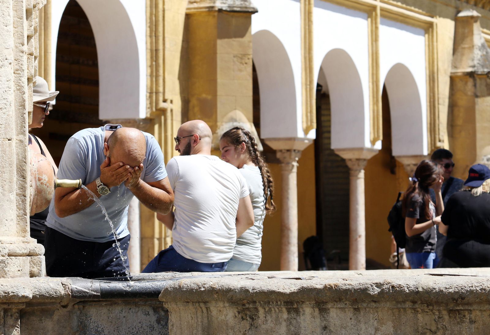 Un hombre se refresca en la fuente del Patio de los Naranjos de la Mezquita.