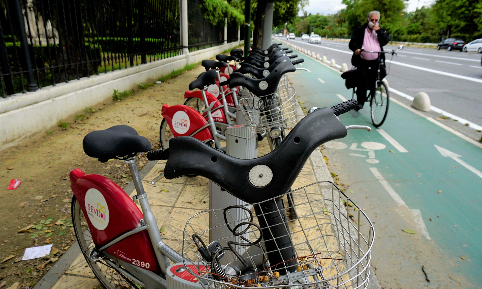 Un ciclista pasa junto a una estación de Sevici en la avenda de la Palmera.