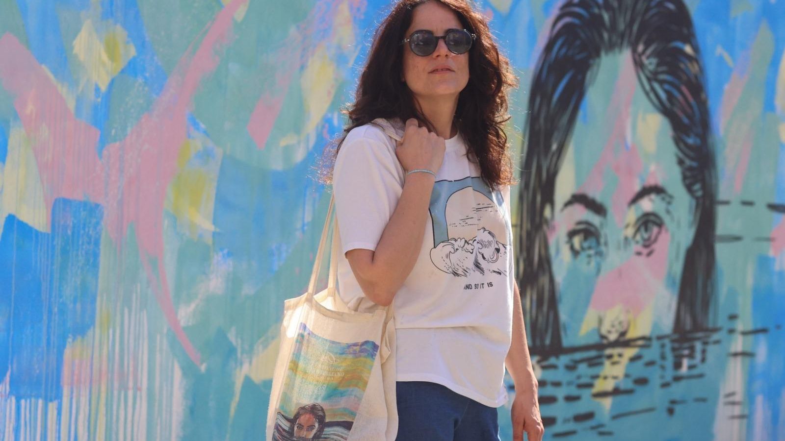 Alice Pasquini posa junto a su mural con una bolsa del Festival de Cine Italiano al hombro.