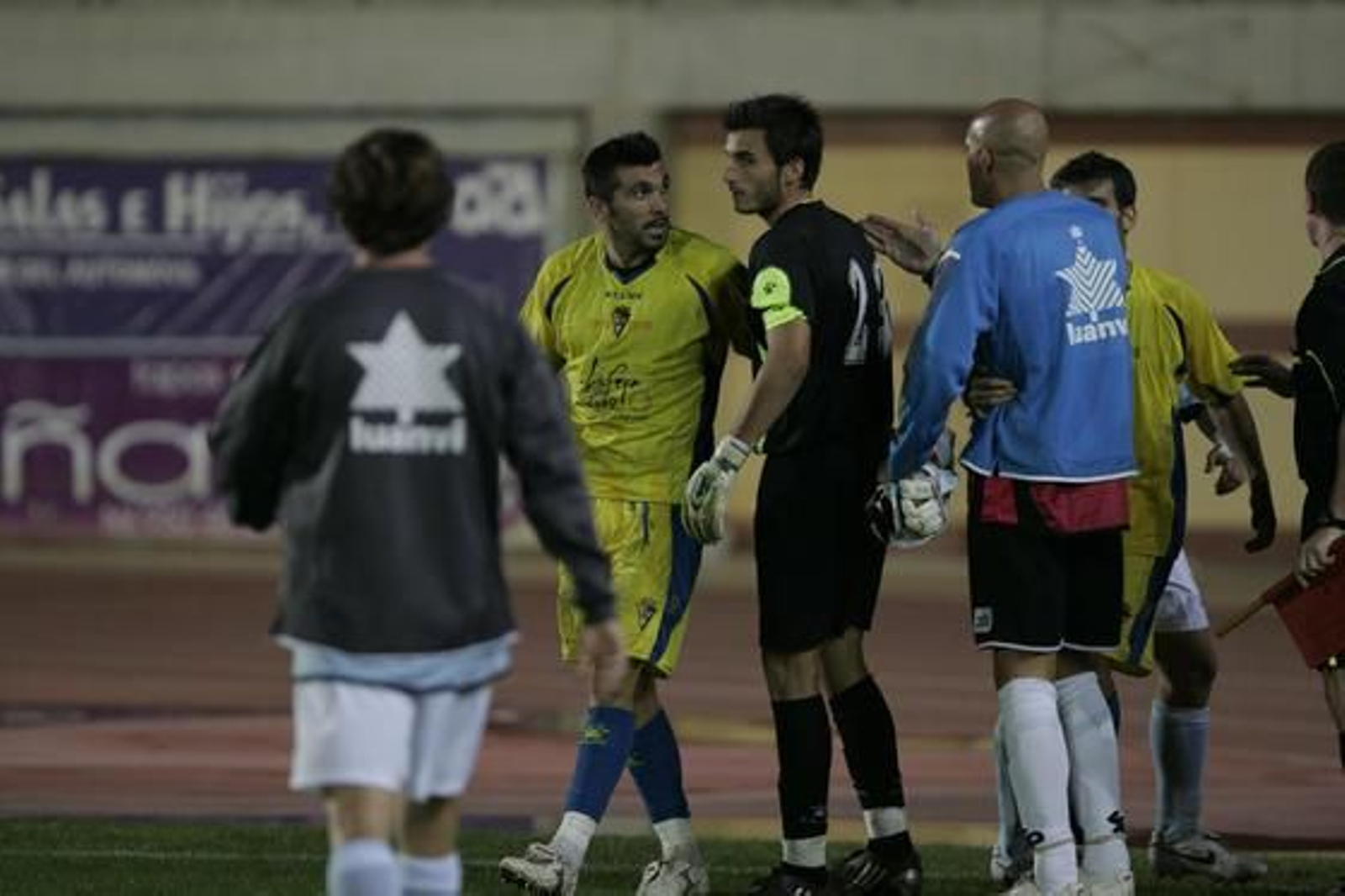 El debutante Serrano se enfrenta a varios jugadores locales mientras intenta calmarle. 

Foto: Javier Alonso