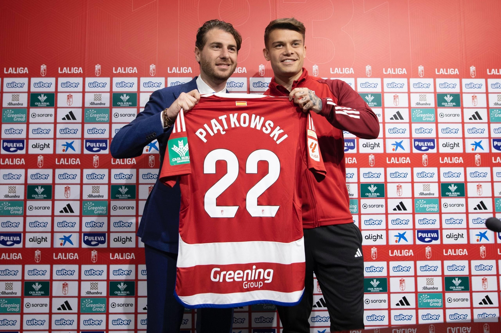 Piatkowski muestra su camiseta junto al director deportivo del Granada