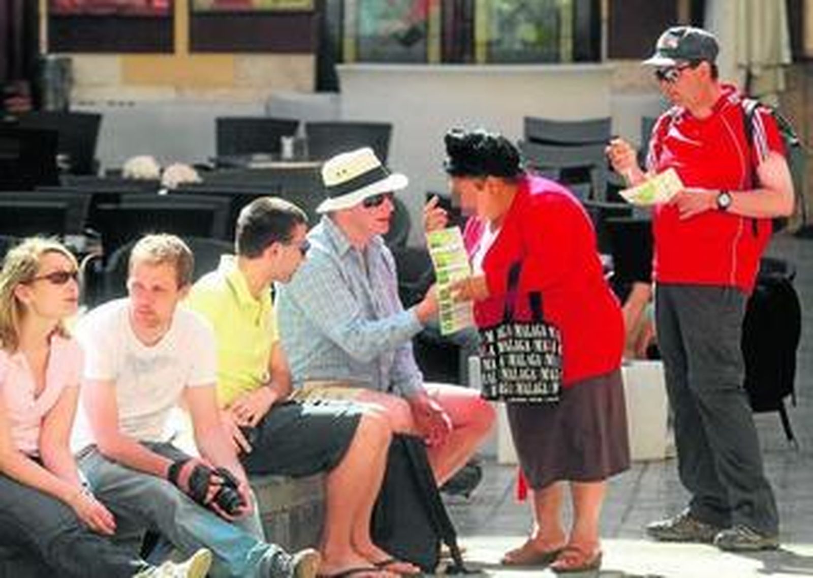 Una mujer vende lotería a un grupo de turistas.