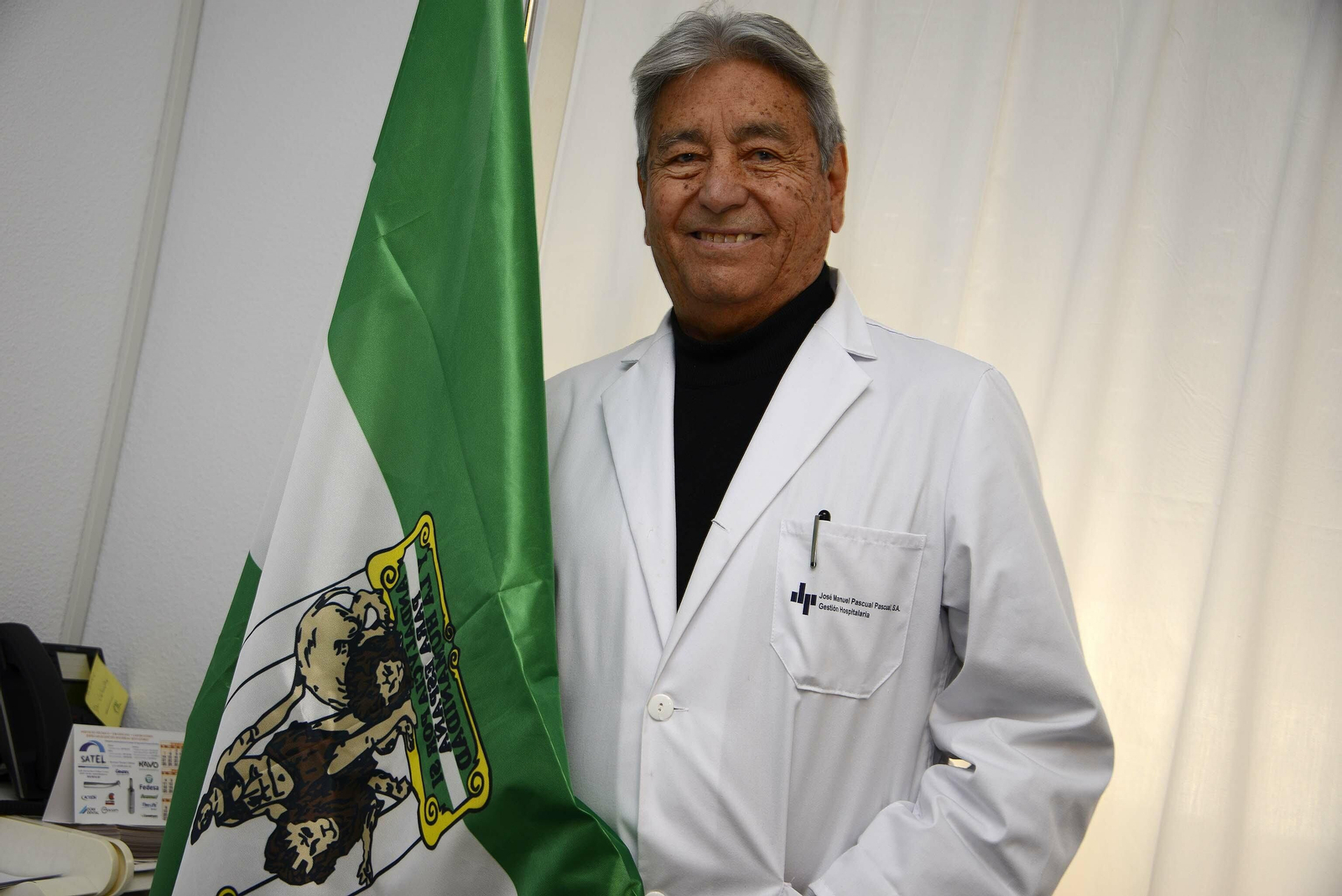 Mario Velarde en su despacho del Hospital San Rafael con la Bandera de Andalucía que recibió el 25 de febrero.