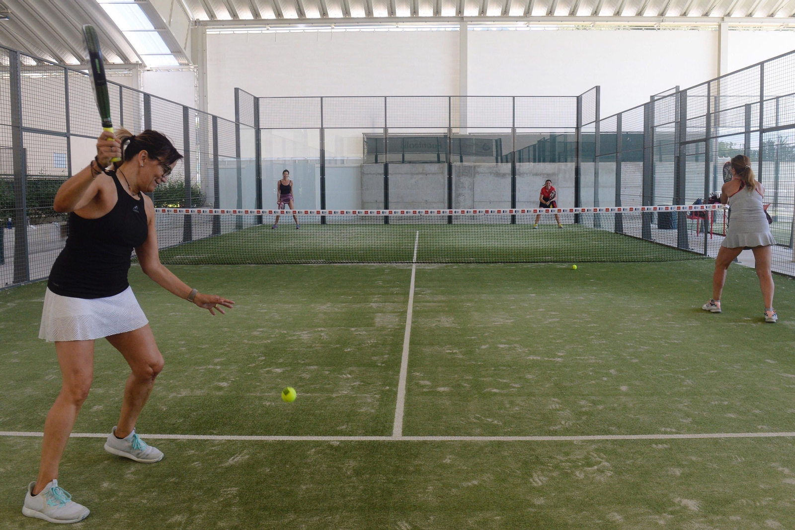 Mujeres jugando hoy lunes un partido de dobles en el Club Raqueta de Valladolid en una pista cubierta.