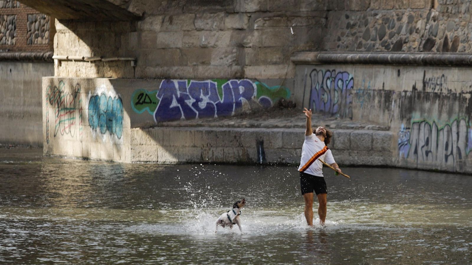 Un hombre juega con su perro en el río Genil