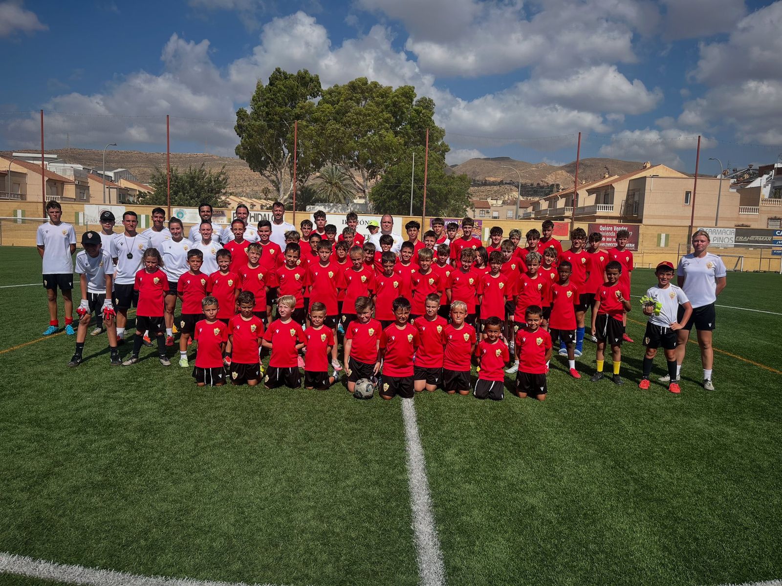 Foto de familia de los participantes al campus de verano de la UD Almería con el técnico del Almería B, Alberto Lasarte.