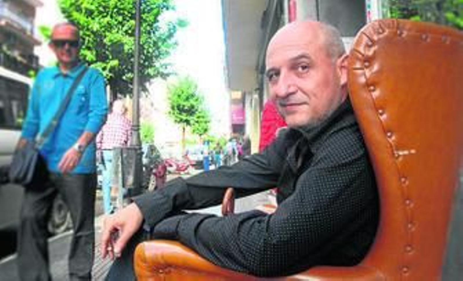 El escritor onubense Mario Marín contempla la vida en su barrio, Isla Chica, sentado en un sillón, en plena avenida José Fariñas.