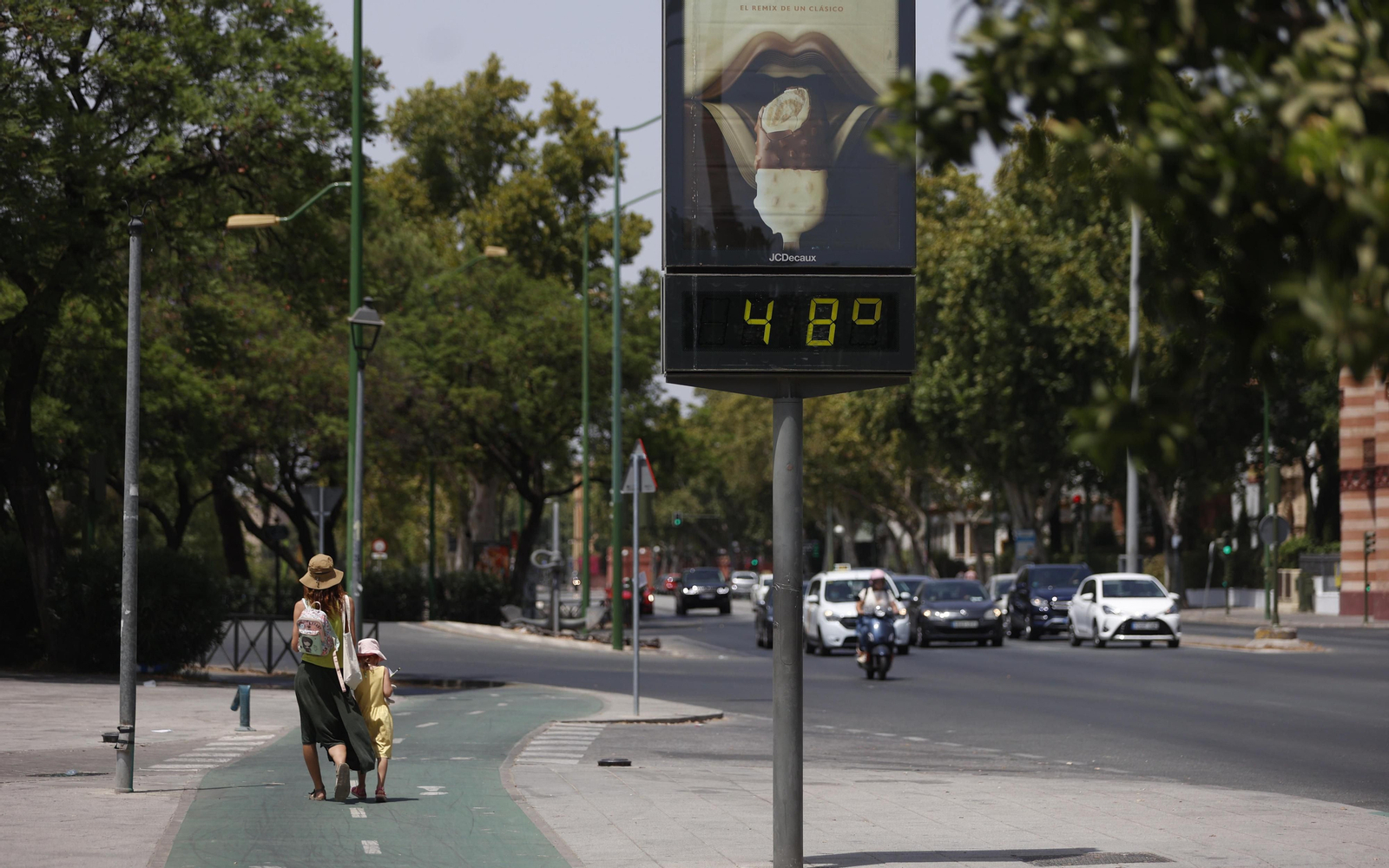 Una mujer y una niña caminan por una solitaria zona de la ciudad a 48 grados este sábado.