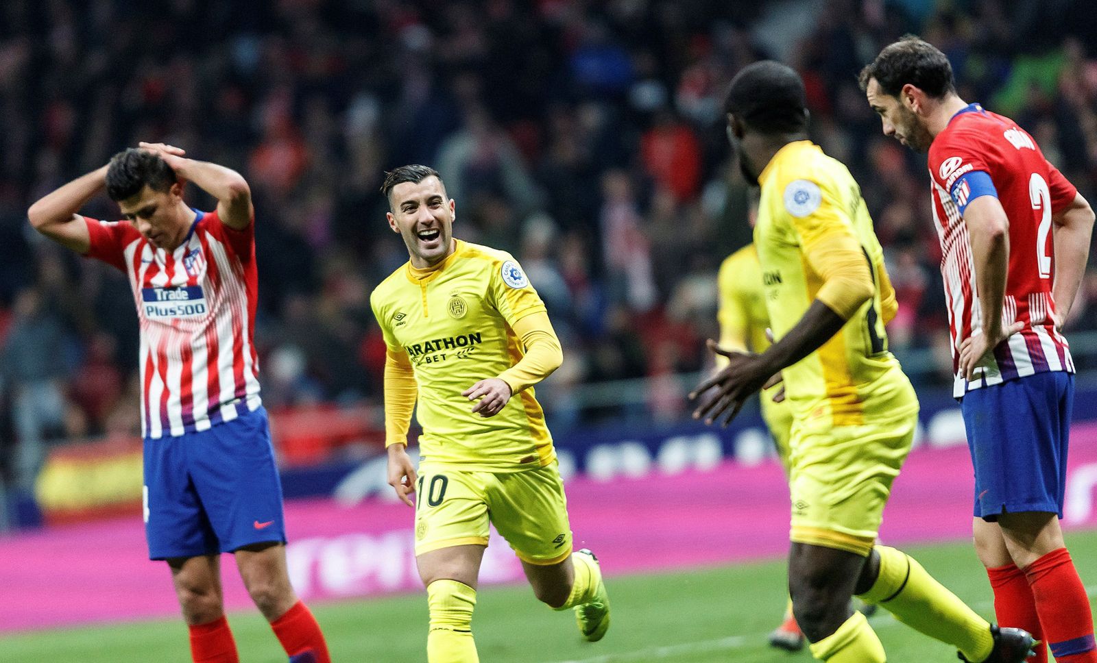 Los jugadores del Girona celebran su gol mientras se desesperan los del Atleti.