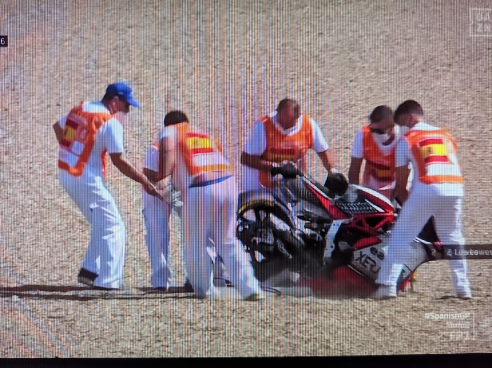 Los comisarios de pista intentan sacar la moto de Manzi de la gravilla.
