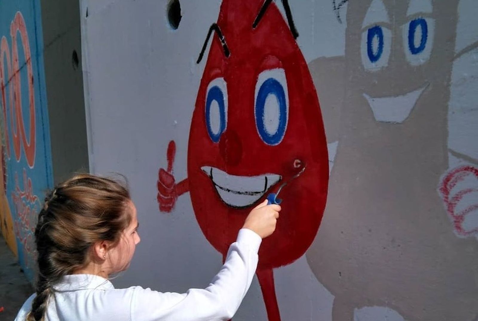 Una de las alumnas pinta el mural de Apo Leu a favor de la donación de sangre y médula.