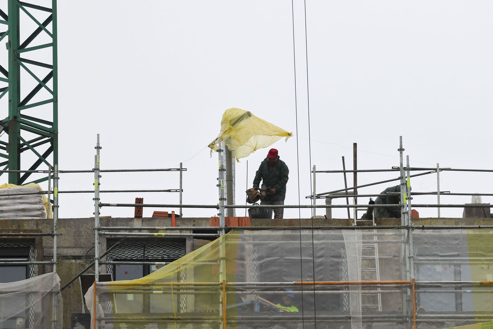 Unos trabajadores en lo alto de un edificio en construcción.