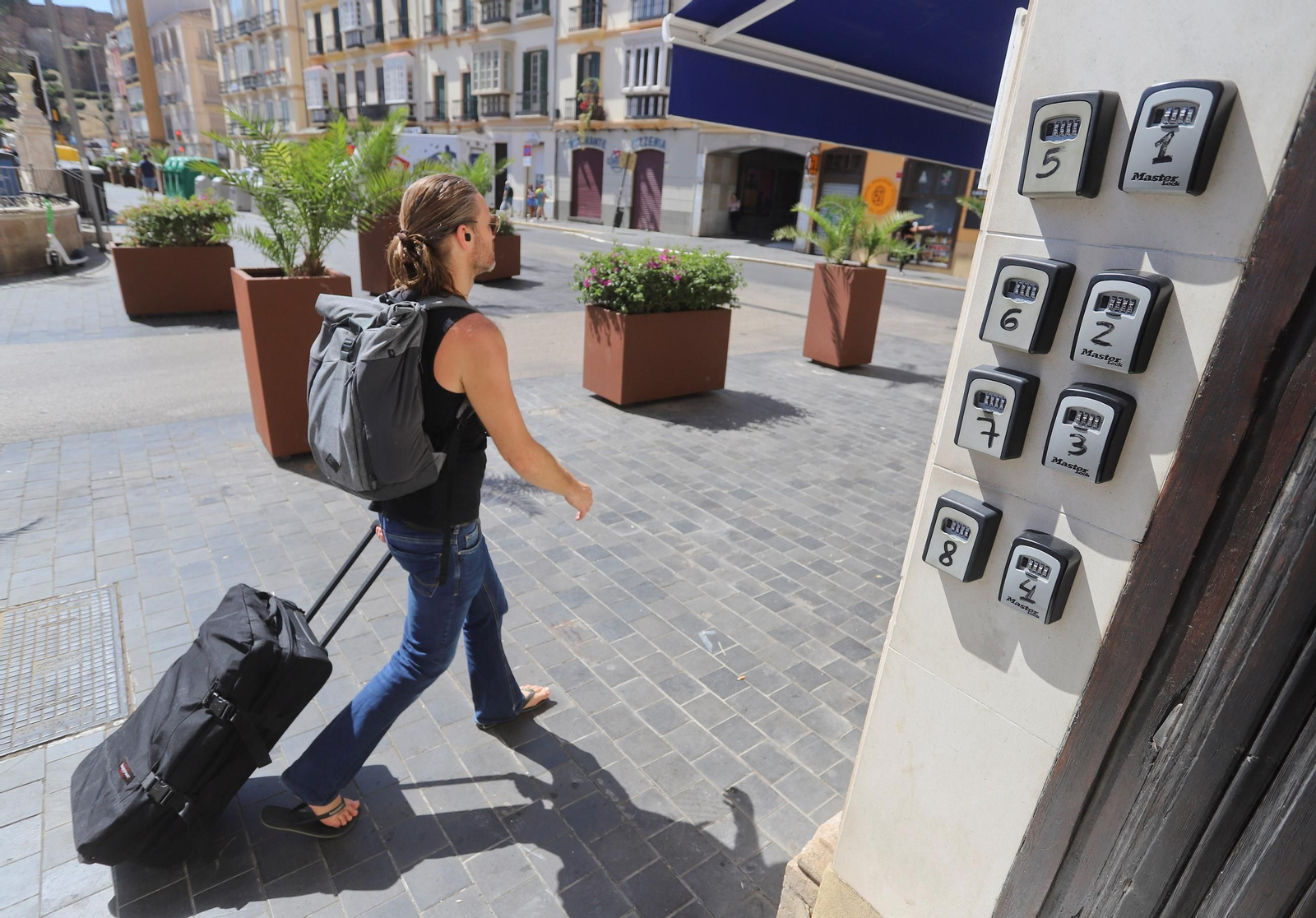Un turista en Málaga pasao junto a un portal con cajas para llaves de pisos turísticos.