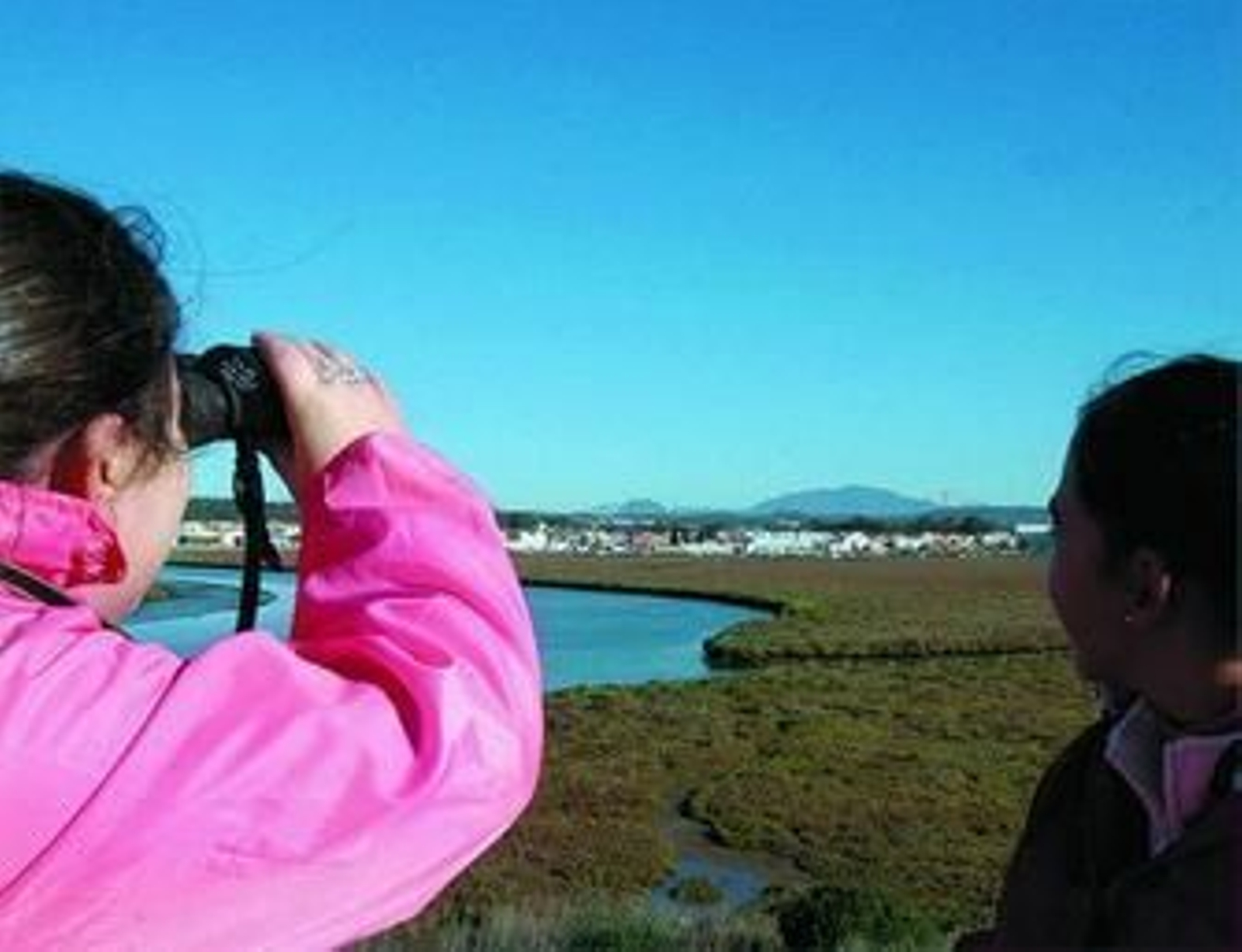 Unas jóvenes divisan las aves migratorias en la zona de El Rinconcillo.