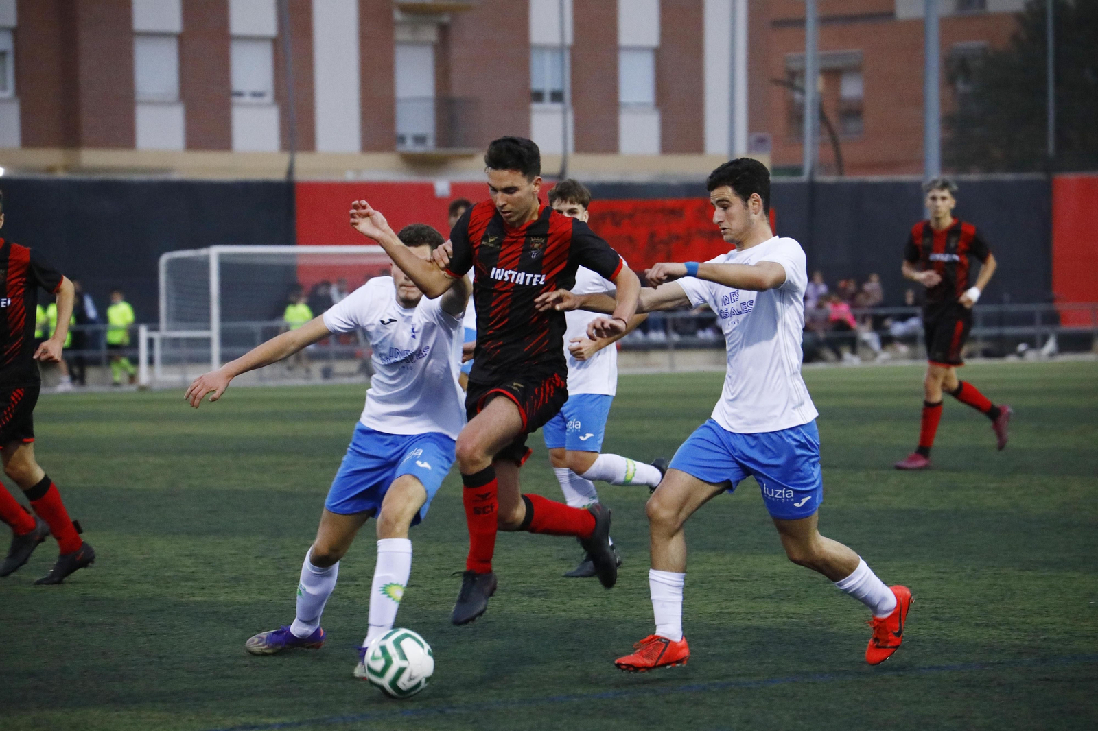 El rojinegro Paquito intenta marcharse de la presión de dos jugadores del Castilleja.