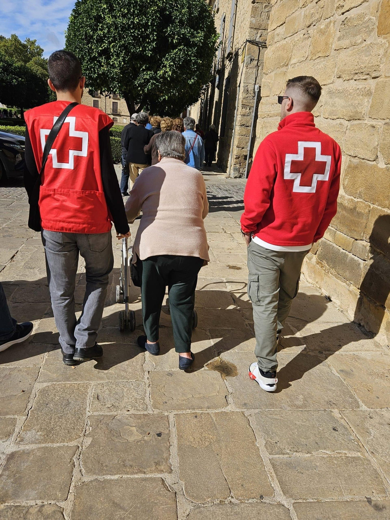 Dos voluntarios de Cruz Roja acompaña a una mujer mayor.