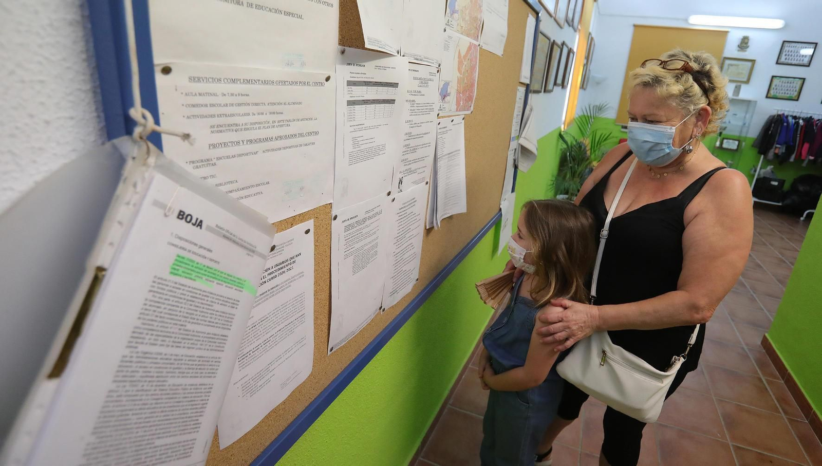 Una pequeña y su responsable, mirando un listado.