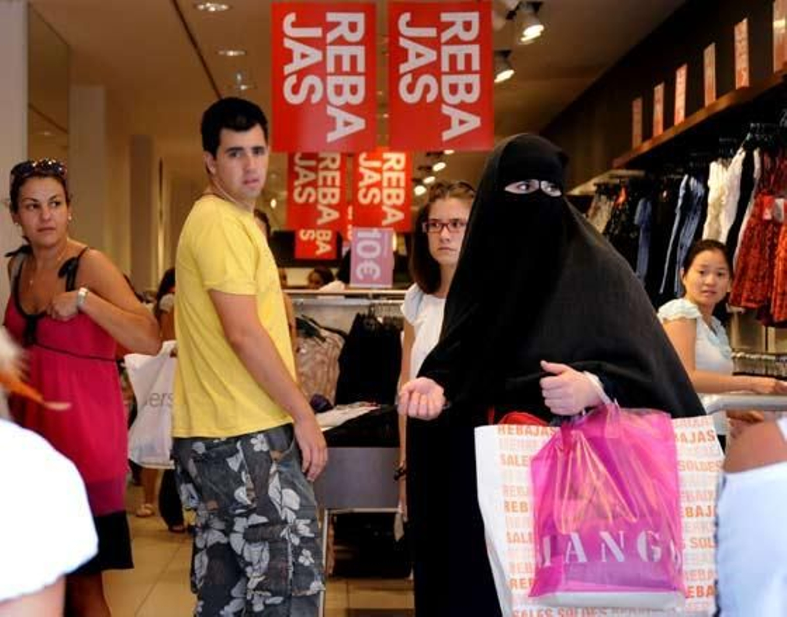 varias personas miran a una mujer cubierta con un burka que también aprovechaba las rebajas para hacer sus compras.  Foto: Juan Carlos Vázquez