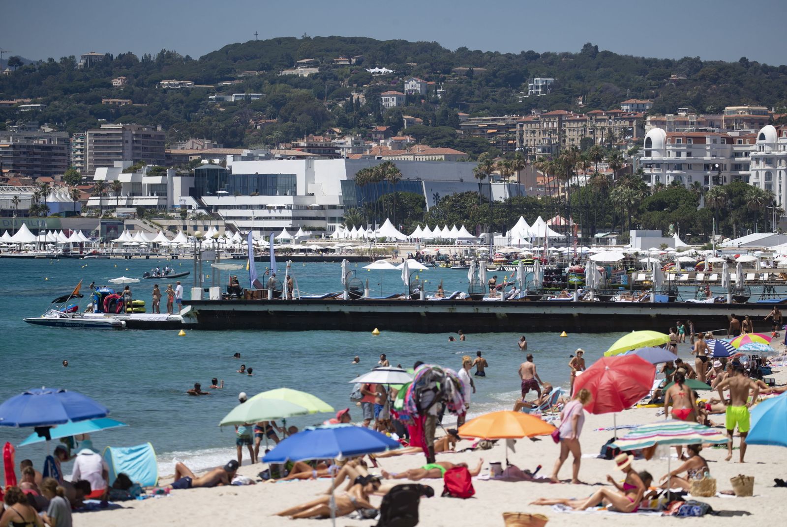 La playa de Cannes llena de veraneantes con el Palacio de Festivales al fondo.