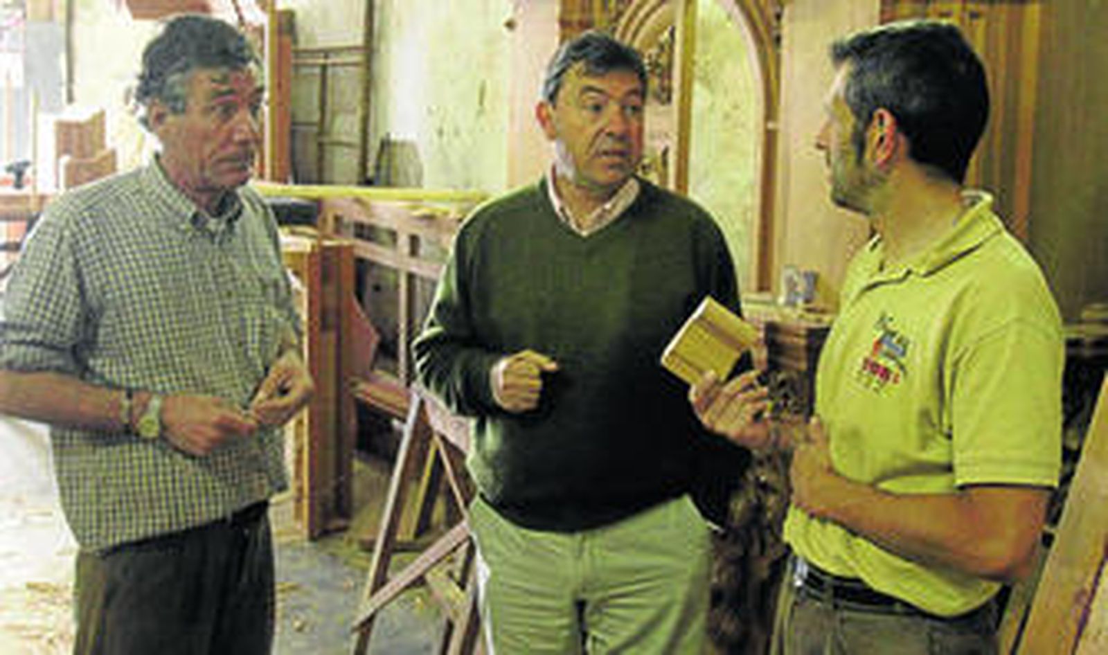 Manuel Guzmán, en el centro, en el taller de madera donde se hace el retablo, con Manuel Rosado, izquierda, y Juan Carretero.