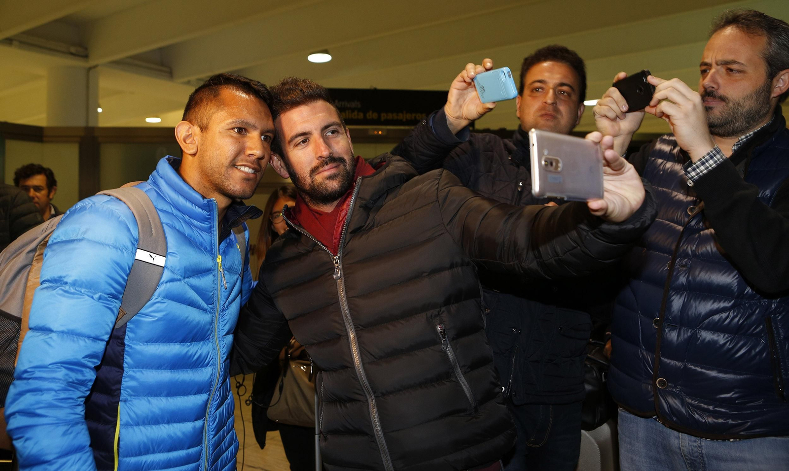 El centrocampista argentino Walter Montoya, a la izquierda, se hace un 'selfie' con un aficionado a su llegada al aeropuerto de San Pablo.