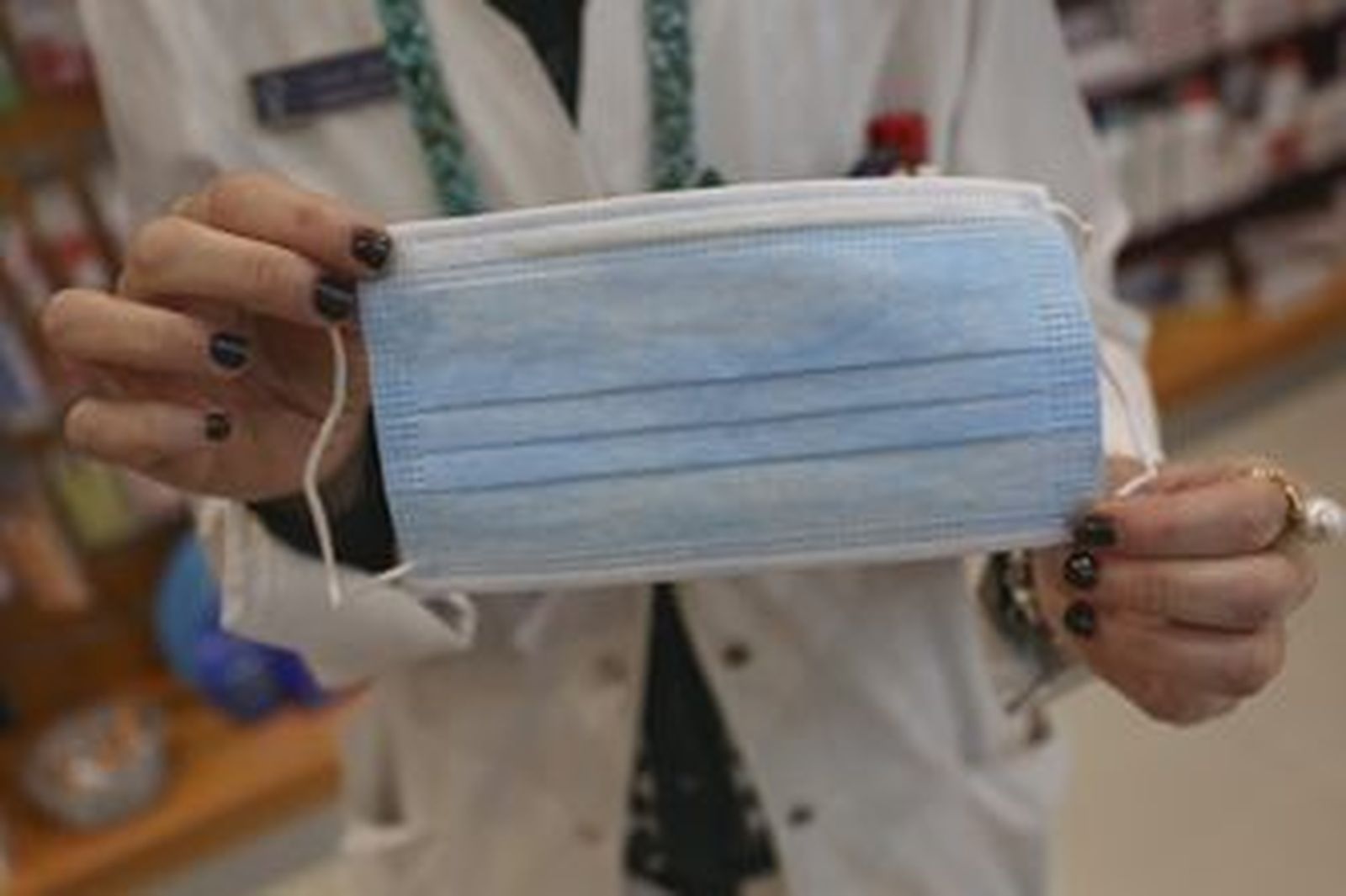 Una sanitaria sostiene una mascarilla.